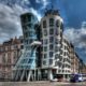 I have about 500 shots of the Dancing House in Prague from every possible angle, portrait and landscape. They've been sitting on my disk for almost 2 years. I didn't know how to process them as the light was not great and an early attempt using Photomatix was a disaster...ISO 100, 14mm, f6.3, (1/1600, 1/400, 1/100 secs)...I chose the f-stop so that I would get fast enough speed for the moving cars. Blended and tonmeppaed in Photomatix using Details Enhancer. Reduced noise in Imagenomics Noiseware. Carefully straightened the vertilcals using the Lens Correction filter in PS as the whole point if the building is it's vertical lines. Used the Freaky Details technique to get lots of details on the windows, etc. Used Nik Viveza to reduce the white glow around the building that was left over from Photomatix processing (masking the clouds). Used 15% Nik Glamour Glow to reduce the harshness of the Photomatix and Freaky Details.